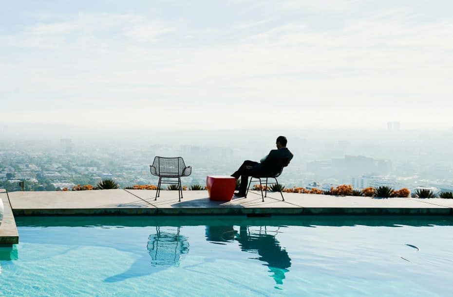 Person relaxing by a pool with a city view, symbolising the high earner not rich yet lifestyle.