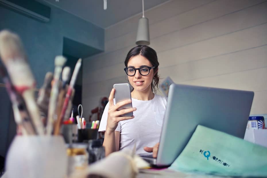A woman in a white shirt uses her smartphone, checking how to get a tax refund.