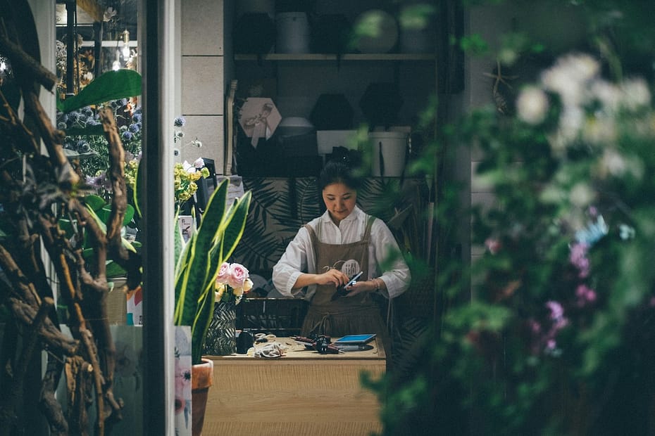 Woman at a business desk with flowers, considering self employed vs limited company options.