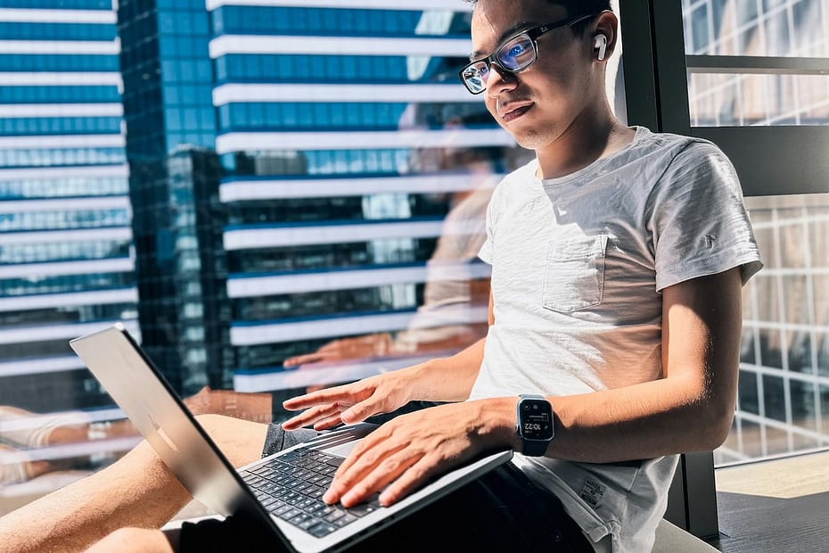 Man sitting in natural light with a laptop, reading about what is self assessment for UK taxpayers.