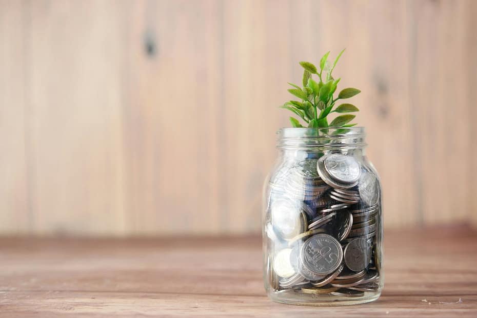 Glass jar filled with coins and a small plant, illustrating the question do you have to pay tax on savings.
