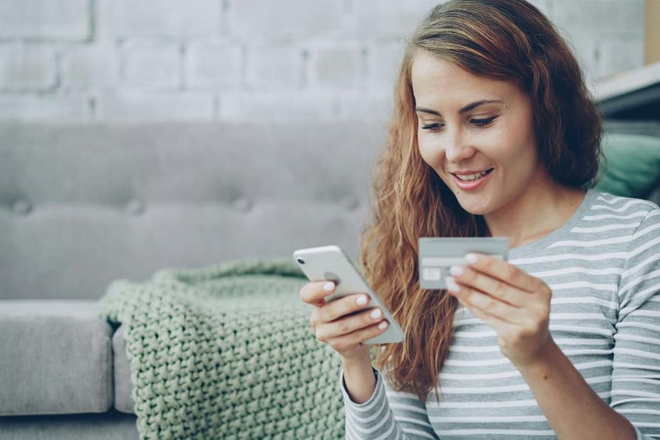 Young woman smiles while using her phone, checking how to get a P800 after overpaying tax.